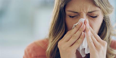 woman is sick with the flu and blowing her nose