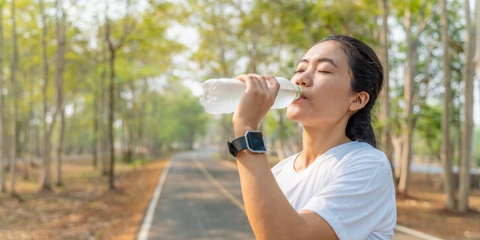 woman drinking water on jogging path