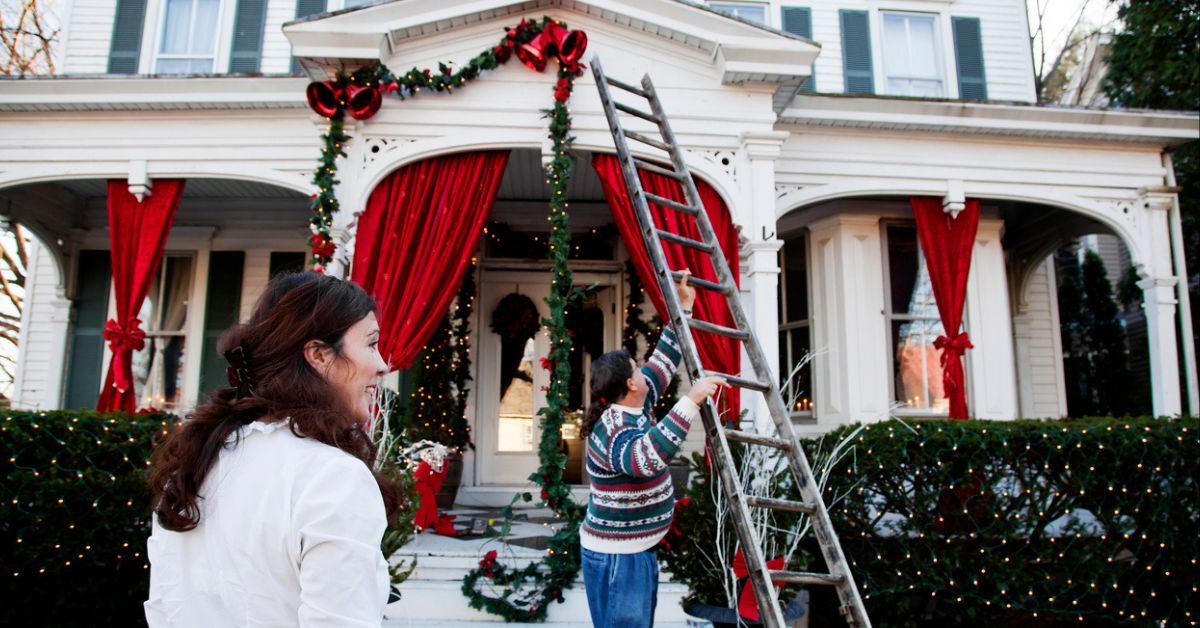 Family with ladder putting up Christmas decorations and hoping not to fall