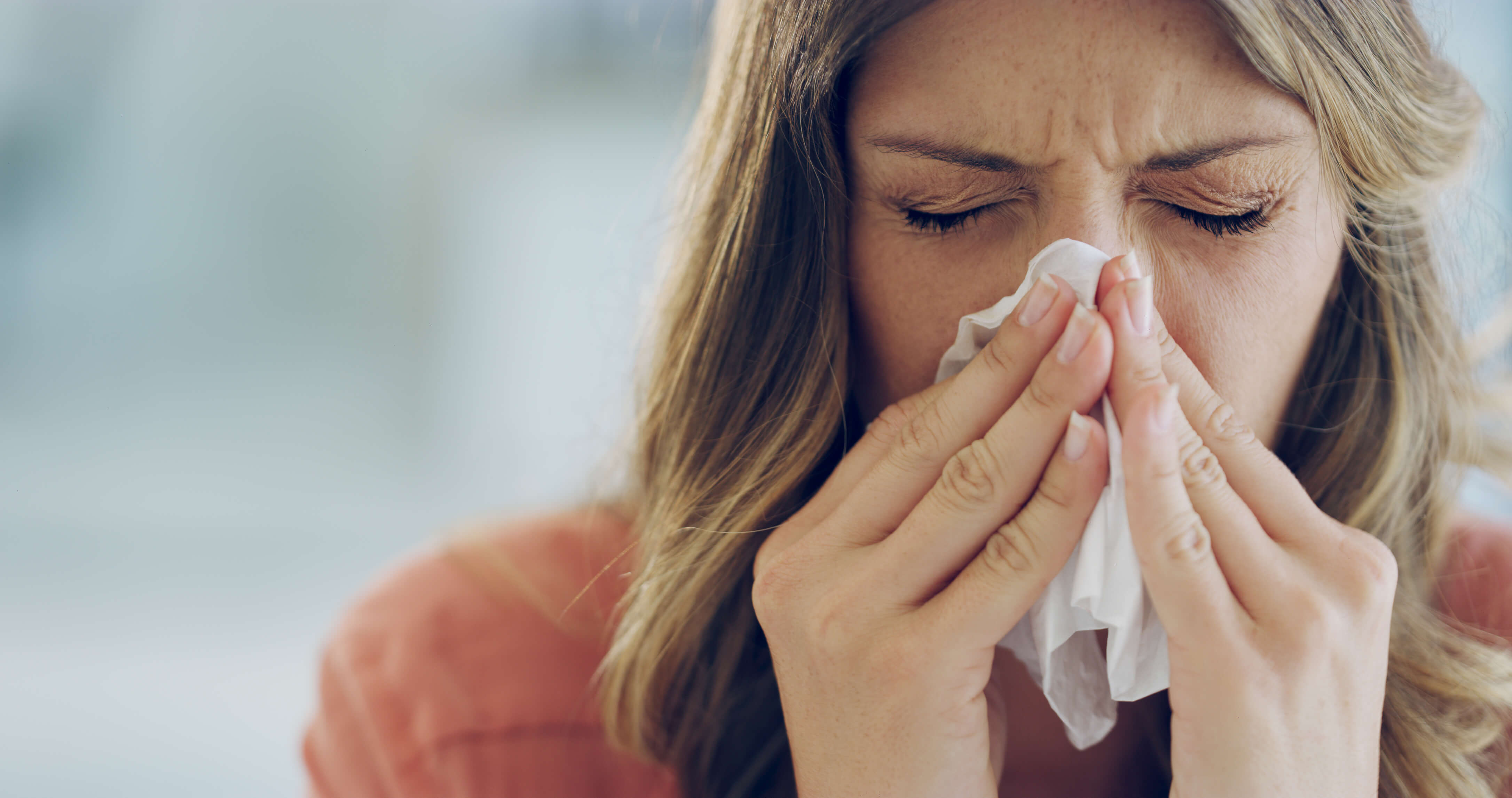 woman is sick with the flu and blowing her nose
