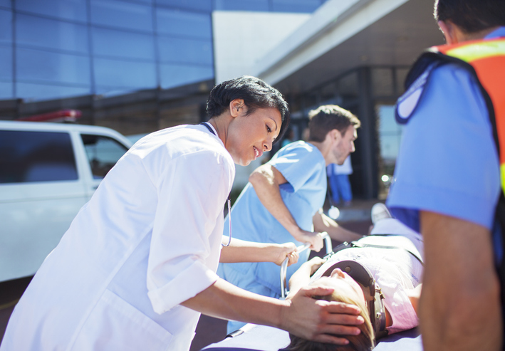 doctor, nurse, and paramedics wheeling patient to hospital