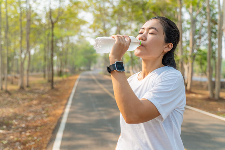 woman drinking water on jogging path